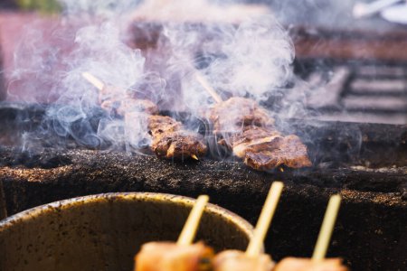 Téléchargez les photos : Photo de brochettes fumeur de viande sur un gril d'une cuisine de rue - en image libre de droit