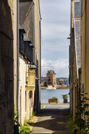 Photo for View through an alley to the harbor and the Vauban Tower in Camaret-sur-Mer, Brittany, France - Royalty Free Image