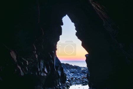 Photo for View out of a cave to the sea with sunset, on the Crozon peninsula, Brittany France - Royalty Free Image