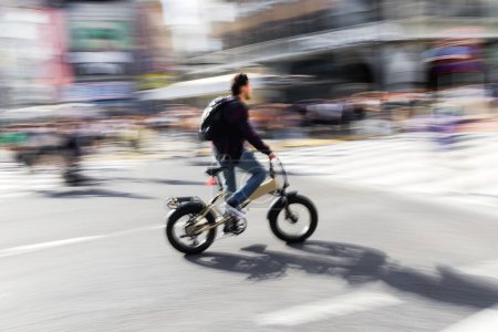 Foto de Imagen con efecto de desenfoque de movimiento intencional de un hombre en una bicicleta que cruza una intersección - Imagen libre de derechos