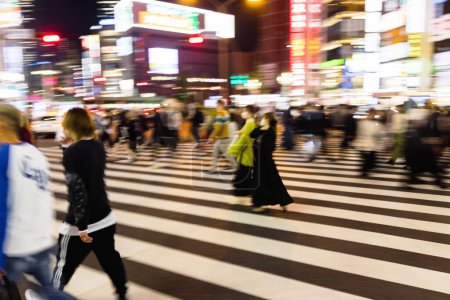 Foto de Imagen con movimiento intencional desenfoque de multitudes de personas cruzando una calle de la ciudad por la noche en Tokio, Japón - Imagen libre de derechos