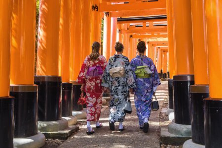 Foto de Kyoto, Japón - 17 de abril de 2023: tres mujeres europeas en Kimono caminando por el camino de Torii en el Santuario Fushimi Inari-Taisha, que es el santuario principal de los kami Inari - Imagen libre de derechos