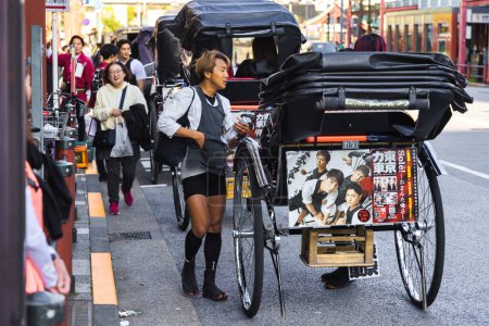 Foto de Tokio, Japón - 09 de abril de 2023: conductor de rickshaw no identificado con un rickshaw en la calle en Asakusa. Los rickshaws son una atracción turística popular en esta zona - Imagen libre de derechos