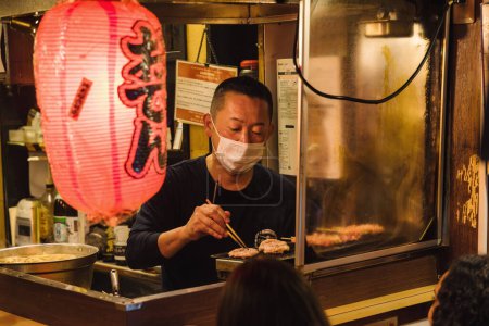 Téléchargez les photos : Tokyo, Japon - 11 avril 2023 : scène nocturne dans une cuisine de rue à Tokyo, au Japon, avec des personnes non identifiées. Tokyo a une industrie alimentaire célèbre avec beaucoup de spécialités et plus de 50.000 restaurants - en image libre de droit