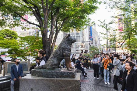 Foto de Tokio, Japón - 11 de abril de 2023: Estatua de bronce de Hachiko en la estación de Shibuya, con personas no identificadas. Hachiko era un perro japonés Akita recordado por su lealtad a su dueño - Imagen libre de derechos