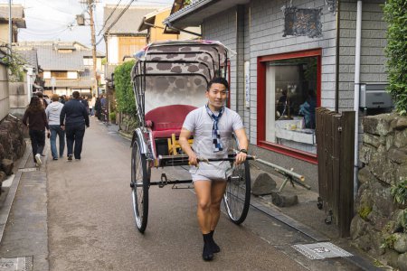Photo for Kyoto, Japan - April 16, 2023: unidentified Japanese rickshaw driver in an alley in Kyoto. By 1872 it was the main mode of transportation in Japan, today it is a tourist attraction - Royalty Free Image