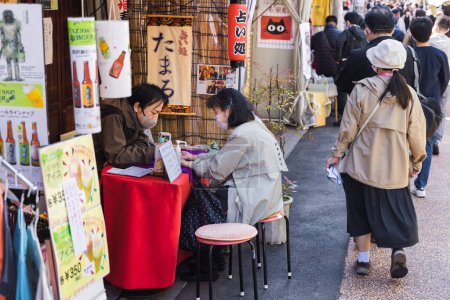 Photo for Tokyo, Japan - April 9, 2023: Fortune teller in Yanaka district and other unidentified people. Yanaka is a district that was spared during World War II and therefore shows the charm of old Japan - Royalty Free Image