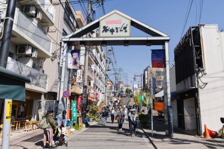 Foto de Tokio, Japón - 09 de abril de 2023: Vista de la calle Yanaka Ginza con gente desconocida, una calle comercial tradicional en el distrito de Yanaka, que se salvó durante la Segunda Guerra Mundial y por lo tanto muestra el encanto del viejo Japón - Imagen libre de derechos