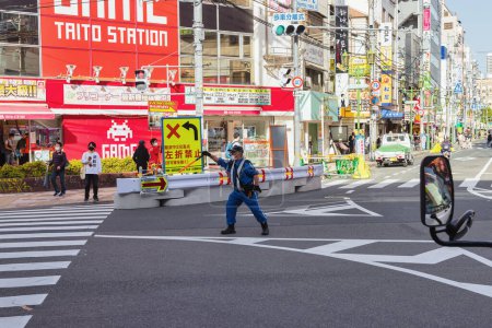 Foto de Osaka, Japón - 13 de abril de 2023: escena callejera con un policía de tránsito en el centro de Osaka con personas no identificadas. Osaka es la tercera ciudad más poblada de Japón - Imagen libre de derechos
