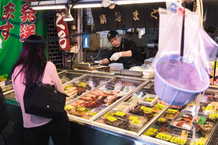 Téléchargez les photos : Tokyo, Japon - 12 avril 2023 : poissonnerie sur le marché aux poissons de Tsukiji avec des personnes non identifiées. C'est une attraction touristique majeure. Avant 2018, c'était le plus grand marché de gros de poisson au monde - en image libre de droit