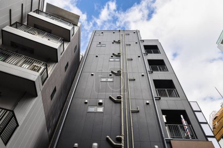 Téléchargez les photos : Photo d'une façade d'un bâtiment résidentiel japonais avec des tuyaux d'égout extérieurs - en image libre de droit