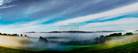 Téléchargez les photos : Brouillard et brouillard recouvrant les collines rurales au lever du soleil - en image libre de droit