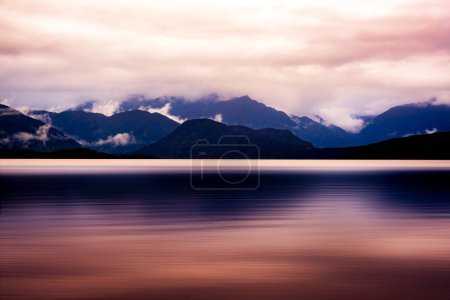 Téléchargez les photos : Lac Kanière magique et lunaire par un après-midi sombre et pluvieux sur la côte ouest de la Nouvelle-Zélande et la chaîne de montagnes des Alpes du Sud - en image libre de droit