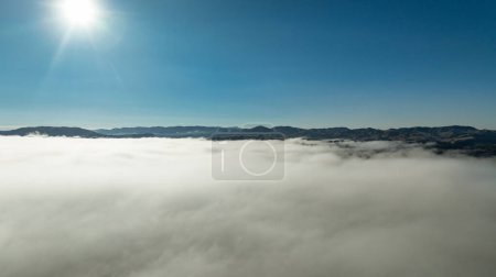 Luftaufnahme einer niedrigen Wolke im Tal mit der Bergkette über den Wolken