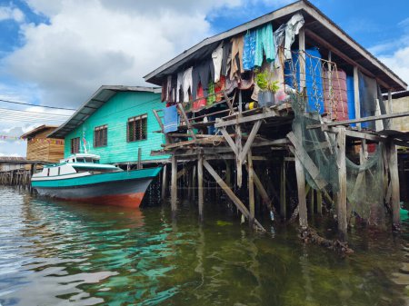 Photo for Fishing boats moored beside a house in the water village homes on the river in Semporna, Sabah - Royalty Free Image