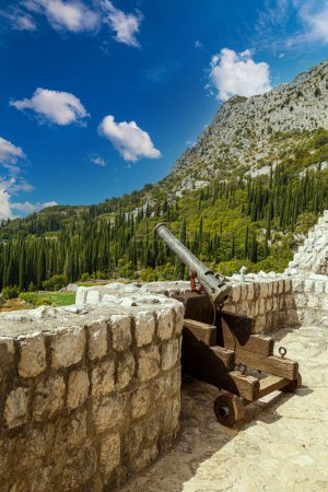 Photo for View on ancient Sokol Grad, Falcon Fortress,  Sokol kula, outdoors - defensive medieval castle in Konavle town near Dubrovnik city.  Croatia.  Cast iron cannon on  roof against  green hills. Tourism destination,  tourist attractio - Royalty Free Image