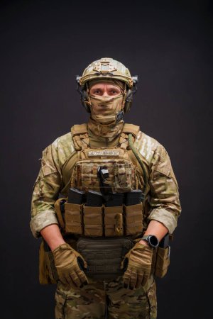  Elitemitglied der Streitkräfte der Ukraine Mann auf schwarzem Hintergrund. Soldat mit militärischer Munition posiert auf schwarzem Hintergrund. Armeesoldat in Tarnkleidung.