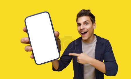 Photo for Smiling young man depicted holding big smartphone in hand, inviting viewer to take closer look. Smartphones screen features white copy space, providing ample room for customized text or graphics - Royalty Free Image