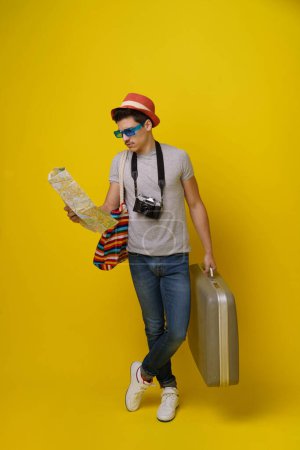 Photo for Student holding map and travel case, dreams about embarking on journey. With map in hand and travel case by side, student is ready to explore new destinations and create unforgettable memories. High - Royalty Free Image