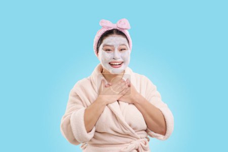 Foto de La mujer feliz usa espuma cosmética en la cara como parte de la rutina de cuidado de la piel, en concepto de cuidado de la piel y limpieza facial. Aislado sobre fondo azul,. Foto de alta calidad - Imagen libre de derechos