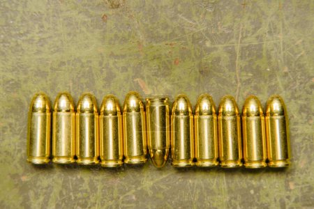 Photo for A group of spent military bullet shells arranged neatly on top of a table surface, displaying various shapes, sizes, and textures. - Royalty Free Image