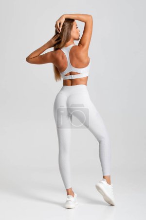 Téléchargez les photos : Femme en forme. Fille athlétique sur le fond gris, vue arrière - en image libre de droit