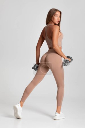 Téléchargez les photos : Femme de fitness sexy. Belle fille athlétique sur le fond gris - en image libre de droit