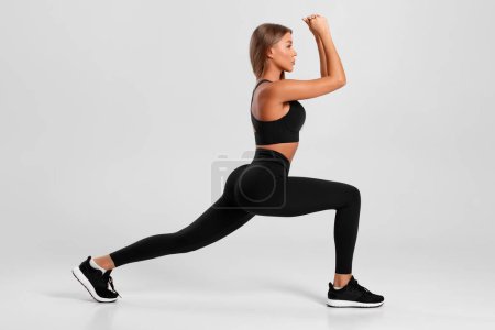 Téléchargez les photos : Femme de fitness faisant des exercices de fentes pour la formation musculaire des jambes. Active fille faisant avant avant une jambe étape fente exercice - en image libre de droit