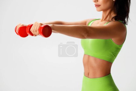 Photo for Athletic girl doing exercise with dumbbells on gray background. Fitness woman working out - Royalty Free Image