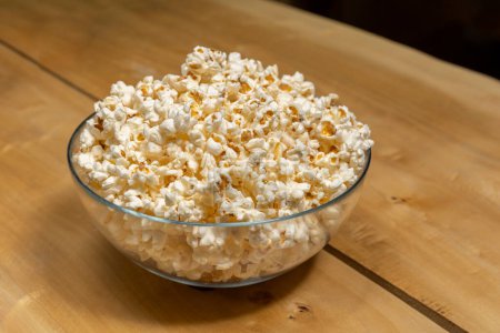 Photo for Popcorns in a glass bowl on wooden table - Royalty Free Image