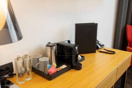 Photo for Coffee machine, tea kettle and water bottles on a table in hotel room - Royalty Free Image