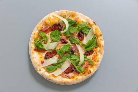 Téléchargez les photos : Pizza au prosciutto à la roquette et tomate sèche - en image libre de droit