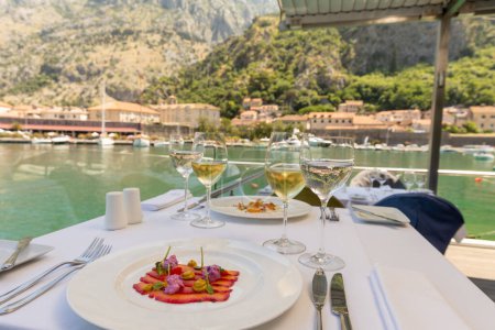 Téléchargez les photos : Filet de poisson sur une assiette servie sur une table de restaurant avec du vin - en image libre de droit