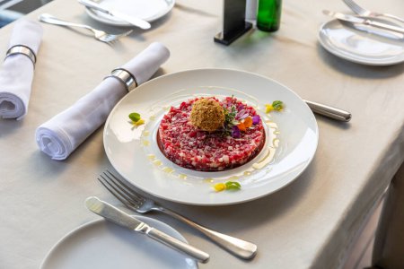 Téléchargez les photos : Boeuf tartare servi sur une assiette blanche dans le restaurant - en image libre de droit