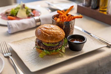 Téléchargez les photos : Burger de boeuf servi avec des frites au restaurant - en image libre de droit