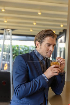 Photo for Handsome businessman drinking whiskey alone in a restaurant - Royalty Free Image