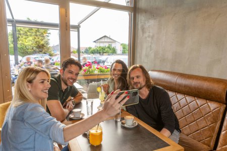 Téléchargez les photos : Jeune femme prenant selfie avec un ami dans un café bar - en image libre de droit