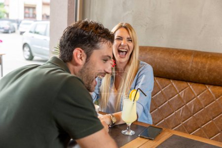 Foto de Feliz pareja romántica sentada en un bar, hablando - Imagen libre de derechos