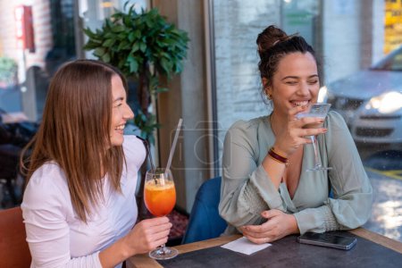Téléchargez les photos : Joyeuses petites amies buvant un cocktail dans un restaurant - en image libre de droit