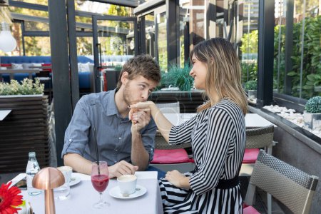 Téléchargez les photos : Homme baisant la main de sa petite amie dans le bar du café - en image libre de droit