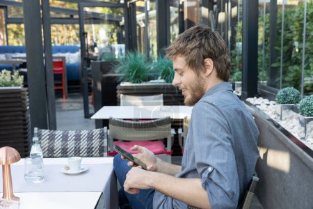 Téléchargez les photos : Jeune homme avec barbe utilisant smarthphone dans un bar de café - en image libre de droit