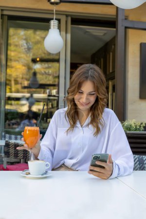 Téléchargez les photos : Beautiful woman texting on her smartphone in a cafe bar - en image libre de droit
