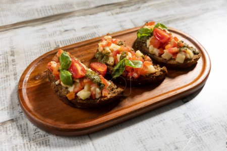 Téléchargez les photos : Bruschetta with cherry tomato and pesto served on a wooden board - en image libre de droit