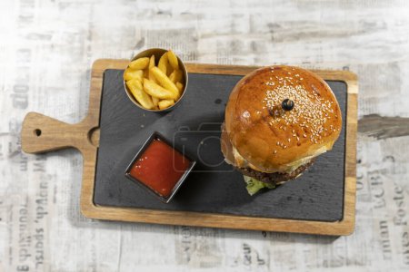 Photo for Beef burger served on a board with french fries in the restaurant - Royalty Free Image