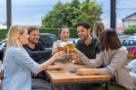 Téléchargez les photos : Des amis heureux buvant de la bière dans un bar - en image libre de droit