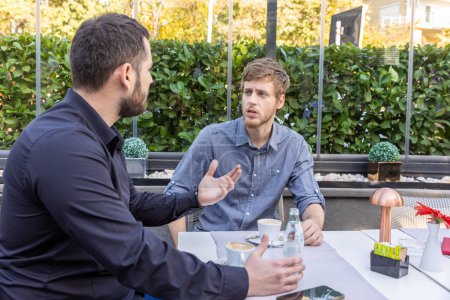 Téléchargez les photos : Deux amis masculins parlent au restaurant - en image libre de droit