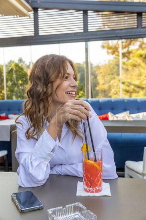 Foto de Mujer joven bebiendo cóctel solo en el restaurante - Imagen libre de derechos