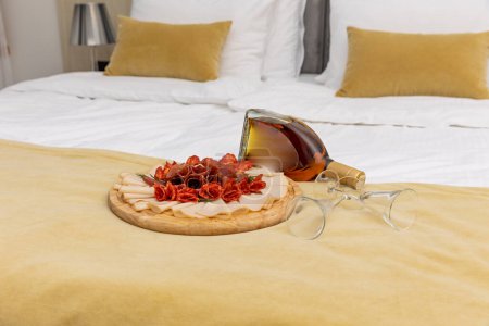 Téléchargez les photos : Viande salée servie sur une planche de bois sur un lit d'hôtel - en image libre de droit