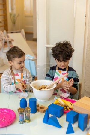 Téléchargez les photos : Enfants préparant de la nourriture à la maternelle montessori, cokies à la banane - en image libre de droit