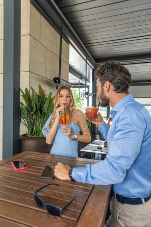 Photo for Business couple drinking cocktails in outdoor restaurant garden - Royalty Free Image